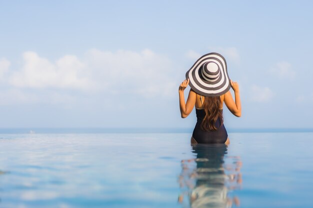 Porträt der schönen jungen Frau, die sich um Schwimmbad im Hotelresort entspannt