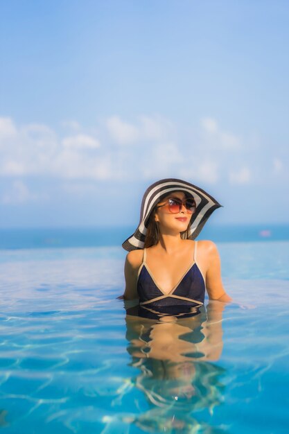 Porträt der schönen jungen Frau, die sich um Schwimmbad im Hotelresort entspannt