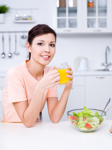 Porträt der schönen jungen Frau mit frischem Orangensaft und gesundem Essen