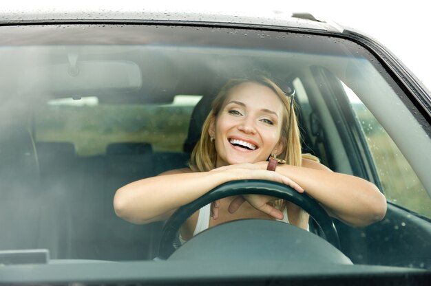 Porträt der schönen jungen glücklichen Frau im neuen Auto - im Freien