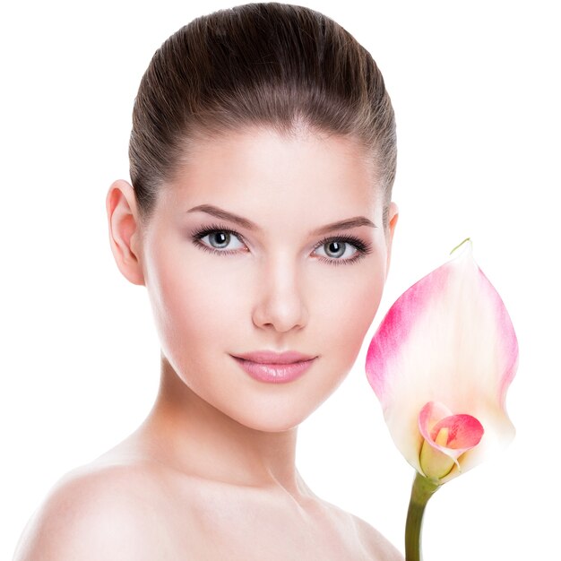Porträt der schönen jungen hübschen Frau mit gesunder Haut und rosa Blumen nahe Gesicht - lokalisiert auf Weiß.
