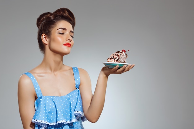 Porträt der schönen Pin-up-Frau, die Kuchen in den Händen hält