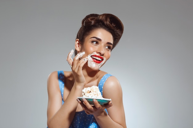 Porträt der schönen Pin-up-Frau, die Kuchen isst