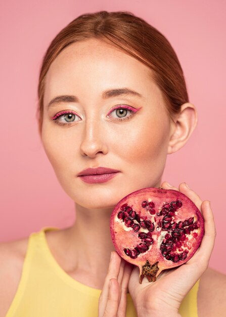 Porträt der schönen rothaarigen Frau, die eine Frucht hält