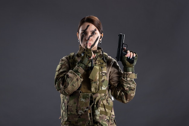 Kostenloses Foto porträt der soldatin in tarnung mit dunkler wand der waffe