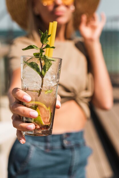 Porträt der stilvollen jungen Frau, die Sommercocktail genießt