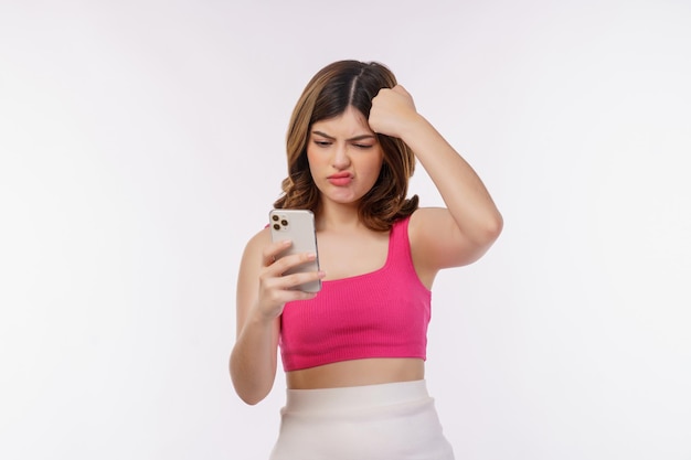 Porträt der verwirrten jungen Frau, die das Handy lokalisiert über weißem Hintergrund verwendet