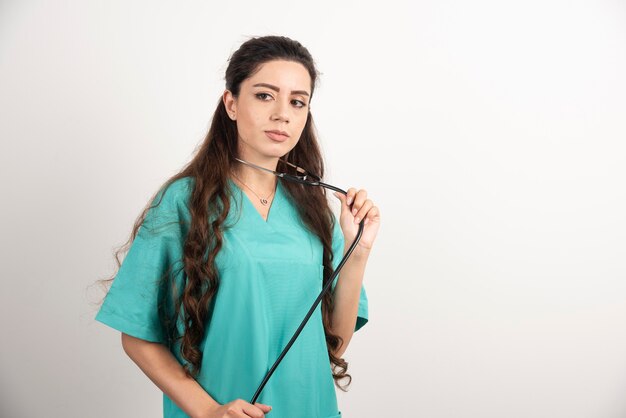 Porträt der weiblichen Gesundheitsfachkraft, die mit Stethoskop aufwirft.