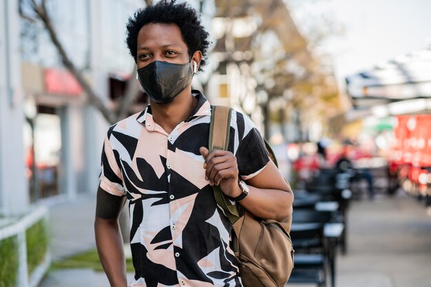 Porträt des Afro-Touristenmannes, der Schutzmaske trägt, während draußen auf der Straße steht