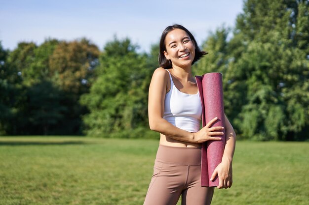 Porträt des asiatischen Mädchens lächelt und lacht steht mit Gummimatte der Sportausrüstung trägt Uniform für w