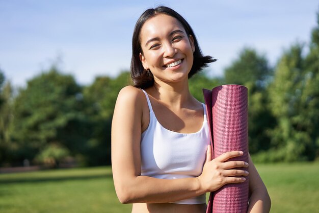 Porträt des asiatischen Mädchens lächelt und lacht steht mit Gummimatte der Sportausrüstung trägt Uniform für w