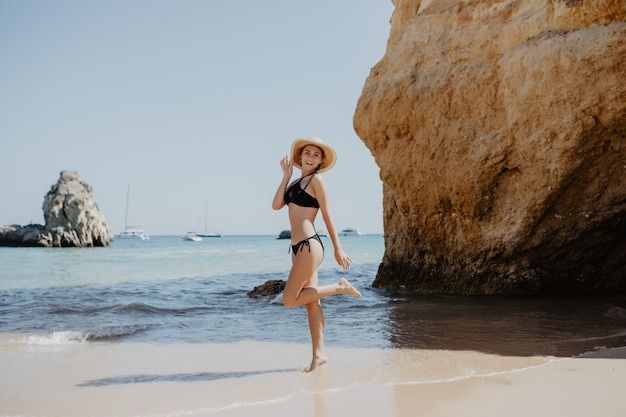 Porträt des attraktiven blonden Mädchens mit dem langen Haar, das auf verlassenem Strand aufwirft.