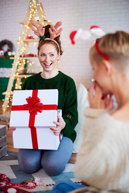 Porträt des aufgeregten Mädchens, das großes Weihnachtsgeschenk öffnet