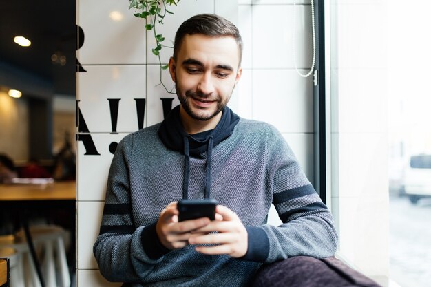 Porträt des bärtigen Mannes mit Handy im Café