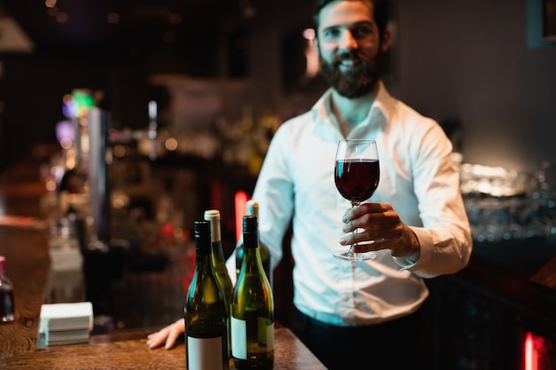 Porträt des Barkeepers, der Glas Rotwein hält