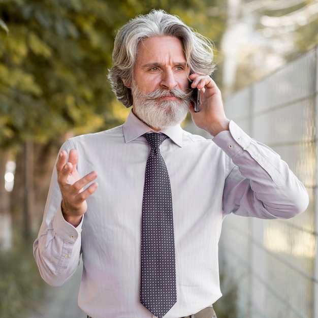 Porträt des eleganten Mannes, der am Telefon spricht