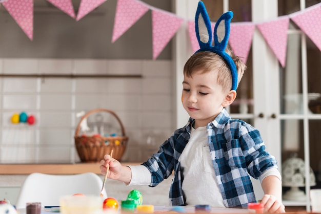 Kostenloses Foto porträt des entzückenden kleinen jungen, der eier malt