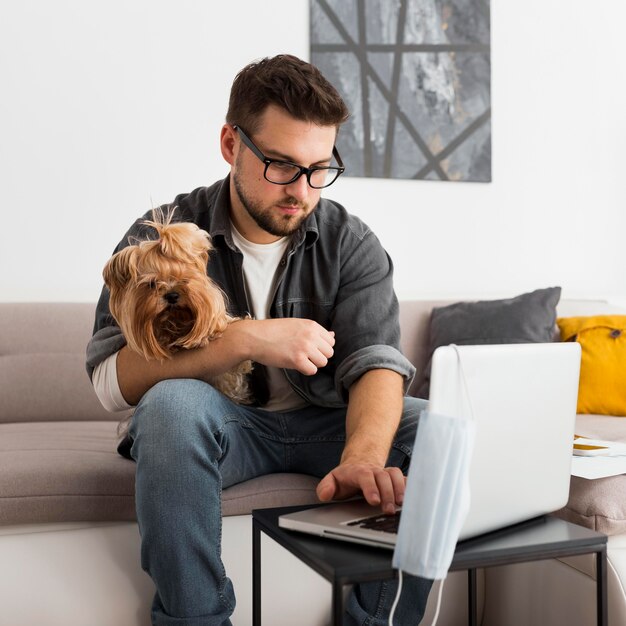 Porträt des erwachsenen Mannes, der Hund hält, während er von zu Hause aus arbeitet