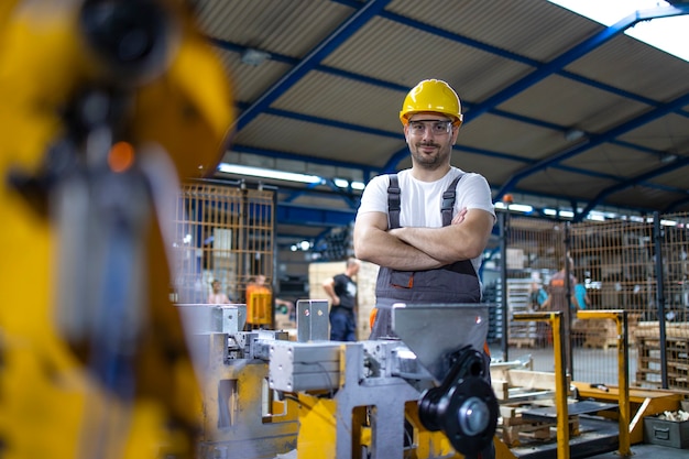 Porträt des Fabrikarbeiters, der zur Industriemaschine steht