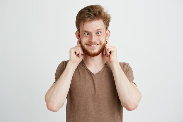 Porträt des fröhlichen fröhlichen jungen Mannes, der lustiges Gesicht täuscht.