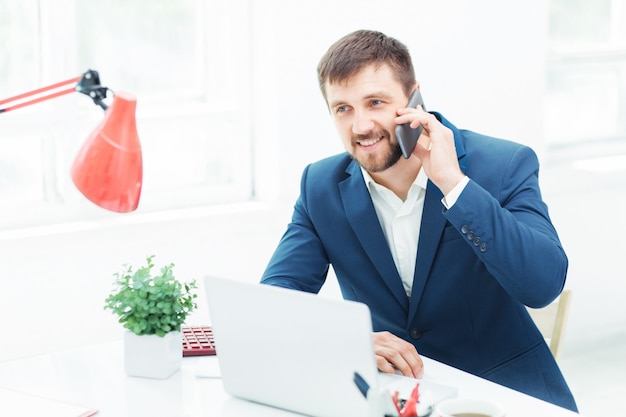 Porträt des Geschäftsmannes, der am Telefon im Büro spricht