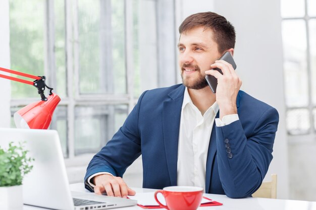 Porträt des Geschäftsmannes, der am Telefon im Büro spricht