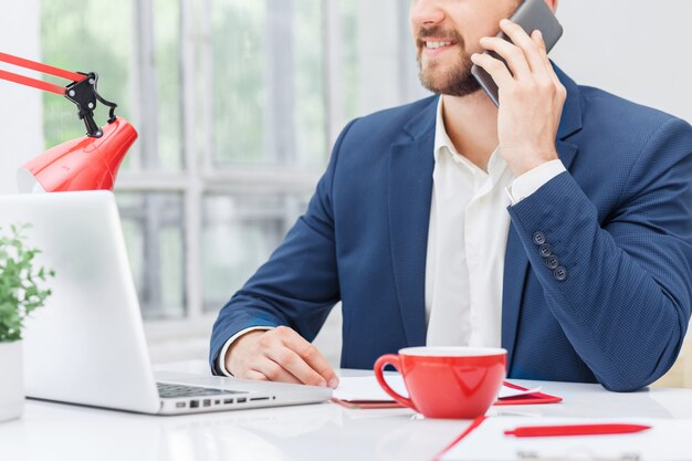 Porträt des Geschäftsmannes, der am Telefon im Büro spricht