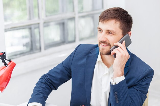 Porträt des Geschäftsmannes, der am Telefon im Büro spricht