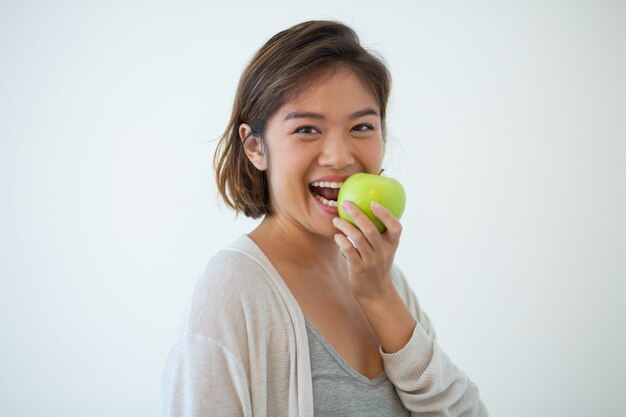 Porträt des glücklichen beißenden Apfels der jungen Frau