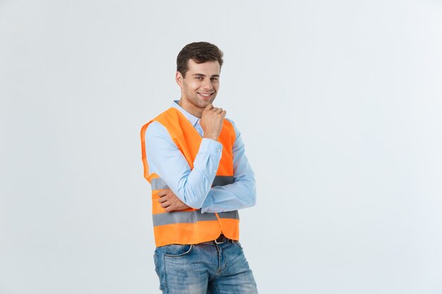 Porträt des glücklichen jungen Vorarbeiters mit der orange Weste lokalisiert über weißem Hintergrund.