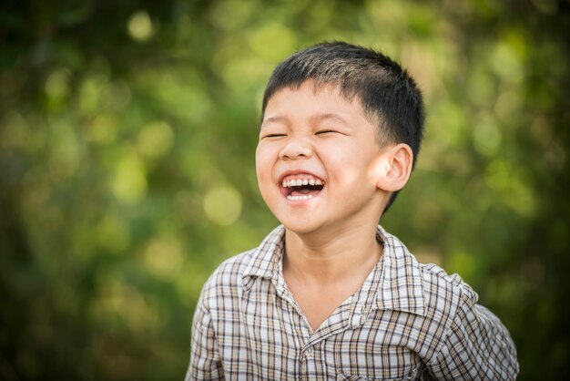 Porträt des glücklichen lachenden kleinen Jungen, während er im Park spielt.