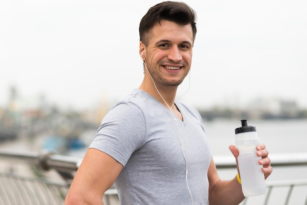 Porträt des glücklichen Mannes, der Wasserflasche hält