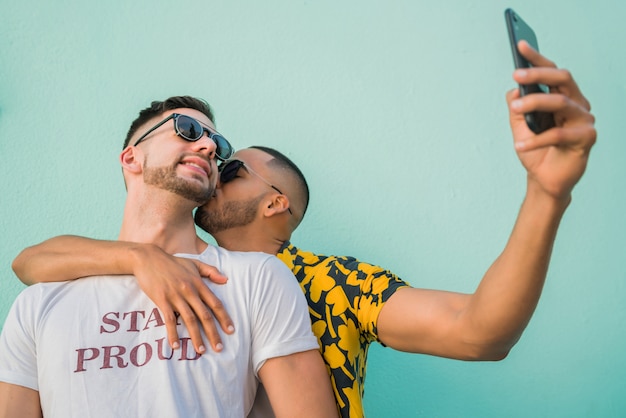 Porträt des glücklichen schwulen Paares, das Zeit zusammen verbringt und ein Selfie mit Handy macht.