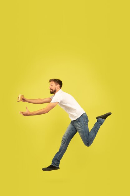 Porträt des glücklichen springenden Mannes in voller Länge auf gelber Wand