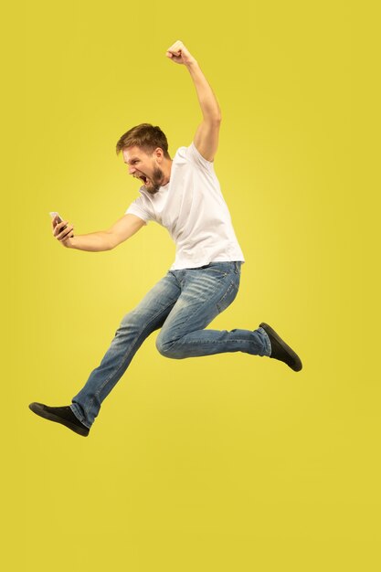 Porträt des glücklichen springenden Mannes in voller Länge lokalisiert auf Gelb