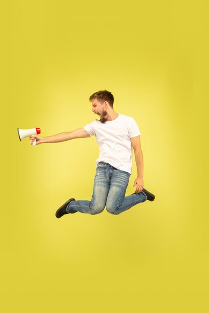 Porträt des glücklichen springenden Mannes in voller Länge lokalisiert auf Gelb
