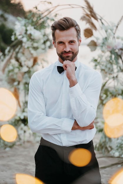 Kostenloses Foto porträt des gutaussehenden bräutigams bei seiner strandhochzeit