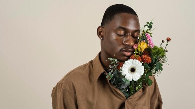 Porträt des gutaussehenden Mannes, der mit Blumenstrauß aufwirft