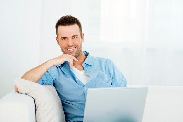 Porträt des gutaussehenden Mannes mit Laptop auf Sofa