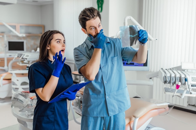 Porträt des gutaussehenden Zahnarztes, der mit ihrem Kollegen steht und Röntgenstrahl hält.