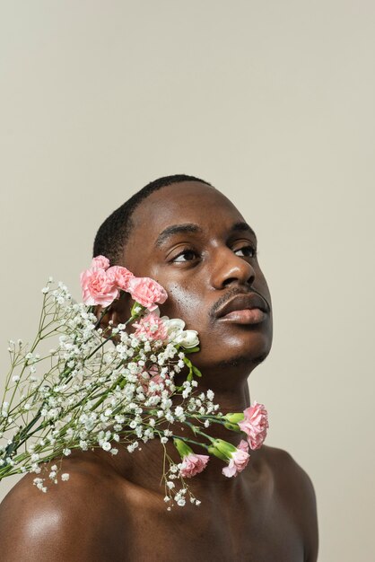 Porträt des hemdlosen Mannes, der mit Blumenstrauß aufwirft