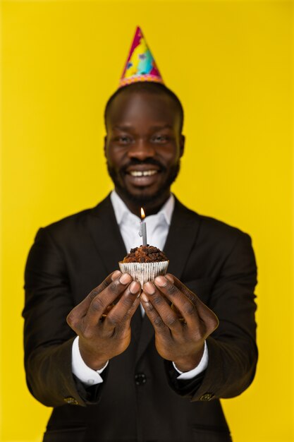 Porträt des hübschen afrikanischen Mannes, der einen Kuchen mit einem Fokus auf dem Kuchen hält