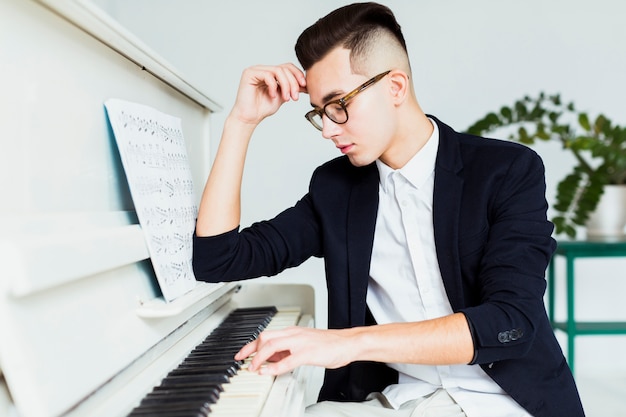 Porträt des hübschen jungen Mannes, der das Klavier spielt