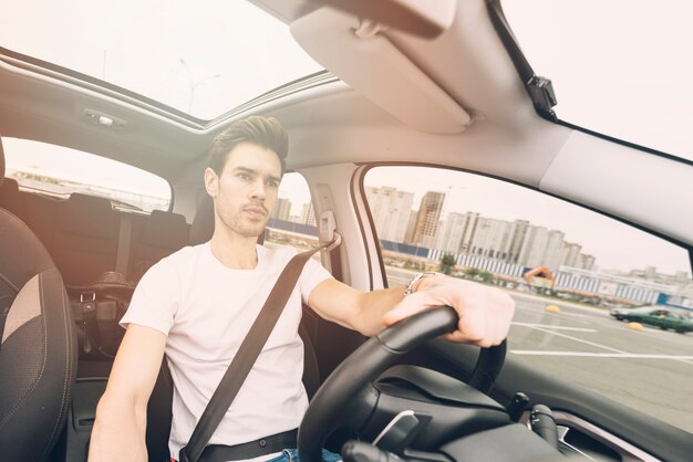 Porträt des hübschen jungen Mannes, der ein Auto fährt