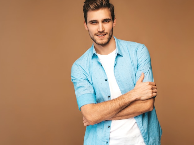 Porträt des hübschen lächelnden stilvollen Modells des jungen Mannes kleidete in der blauen Hemdkleidung an. Mode Mann posiert. Verschränkte Arme