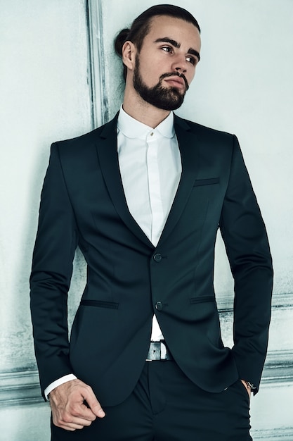 Porträt des hübschen modischen Hipster-Geschäftsmannmodells der Mode, gekleidet im eleganten schwarzen Anzug.