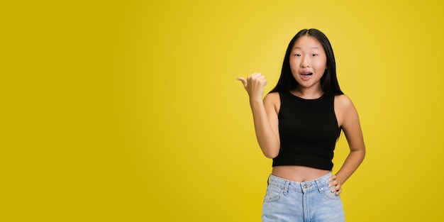 Porträt des jungen asiatischen Mädchens lokalisiert auf gelbem Studio