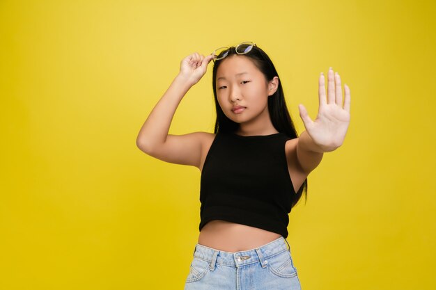 Porträt des jungen asiatischen Mädchens lokalisiert auf gelbem Studio
