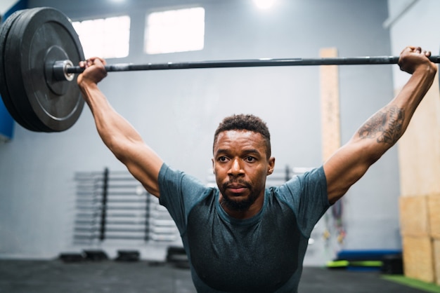 Porträt des jungen Crossfit-Athleten, der Übung mit einer Langhantel macht. Crossfit, Sport und gesundes Lifestyle-Konzept.