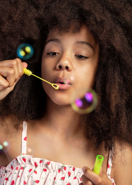 Porträt des jungen entzückenden Mädchens, das beim Spielen mit Seifenblasen aufwirft
